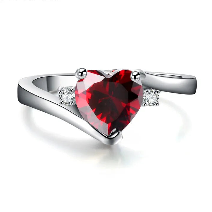 Silver ring with a heart-shaped red gemstone on a white background