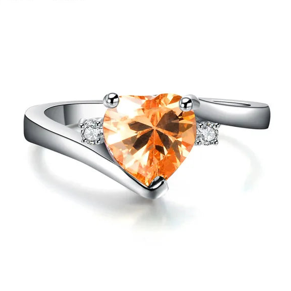 Silver ring with a heart-shaped orange gemstone on a white background
