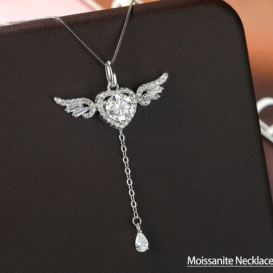 Silver necklace with heart pendant and wings on a black background, branded 'Serenity Day'.
