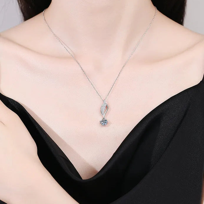 Silver necklace with a pendant worn by a person in a black top.