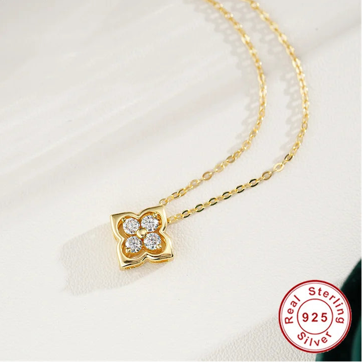 Gold necklace with a clover-shaped pendant on a white background, featuring the Coderia brand.