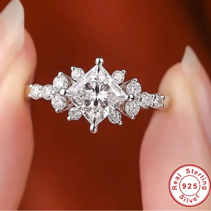 Silver ring with a large central diamond and smaller diamonds on a blurred background