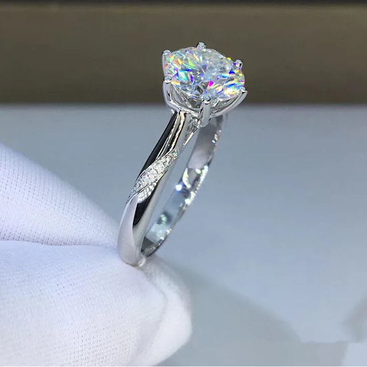 Silver ring with a large diamond on a white surface, brand 'CODERIA' visible.