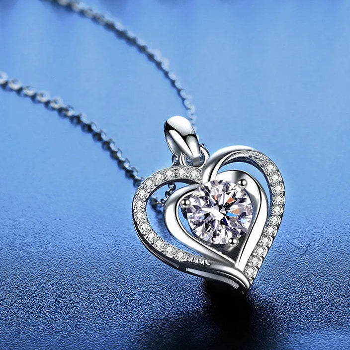Silver heart-shaped pendant with a central gemstone on a blue background, featuring the brand 'CODERIA'.
